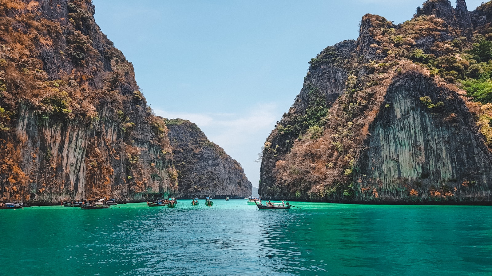 Boat at anchor beneath limestone rock formations in the calm Gulf of Thailand