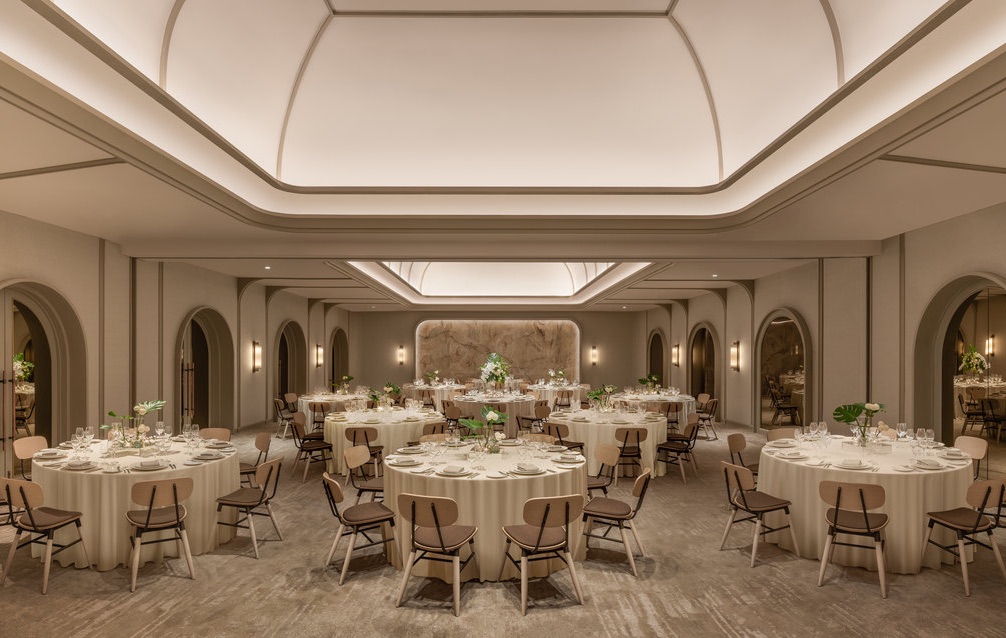 The event hall at Centara Reserve Samui set for a wedding dinner, round banquet tables under a softly lit domed ceiling between arched alcoves